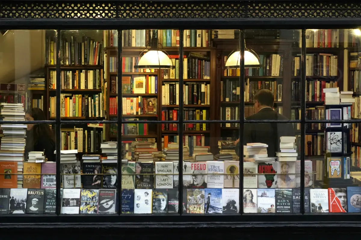 An old-timey bookshop is shown from the street with books in the window.