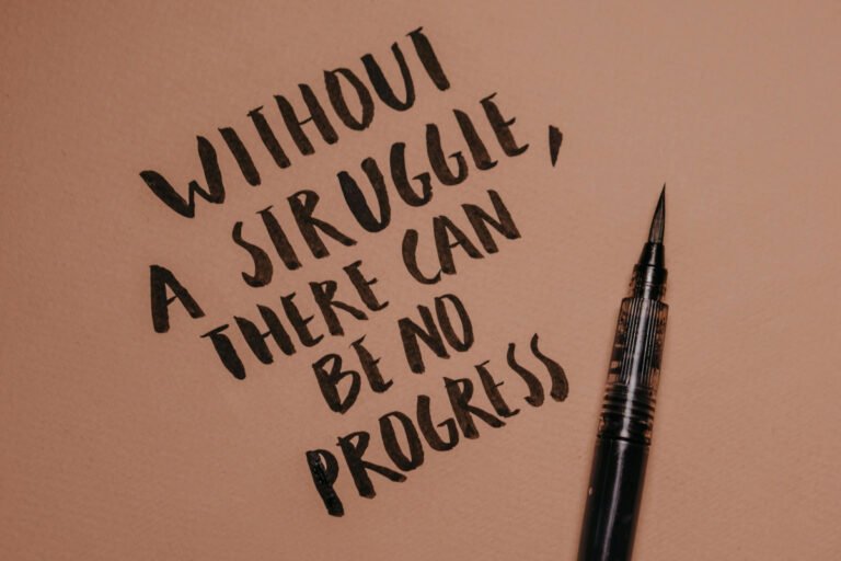 A quote is written in ink on beige paper with a pen beside it.